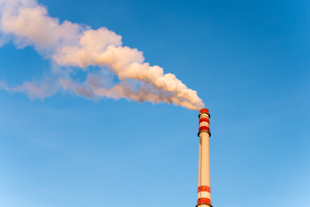 Industrial chimney smoking on sunny winter day