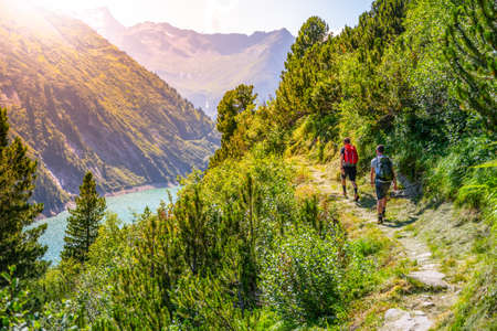 Alpine track and two hikers at mountain lakeの写真素材