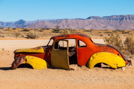 Rustic, weather-beaten cars lie abandoned amidst the stark landscape of Solitaire in Namibia, their vibrant colors contrasting with the arid desert backdrop.の写真素材