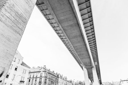 The Nusle Bridge in Prague spans above with its massive concrete structure, casting shadows on the buildings below. Prague, Czechia. Black and white image.の写真素材