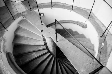 A unique double helix staircase spirals gracefully, showcasing its intricate design. The stone steps and railings create an inviting atmosphere in the interior space.の写真素材