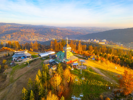 The Tanvaldsky Spicak Lookout Tower stands amidst vibrant autumn foliage in the Jizera Mountains, offering stunning views of the surrounding landscape in the evening light.の写真素材