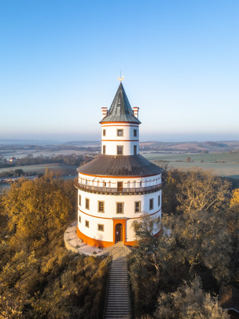 The elegant Baroque chateau of Humprecht rises above Sobotka, surrounded by colorful autumn trees as the sun rises, illuminating the landscape and creating a serene atmosphere.の写真素材