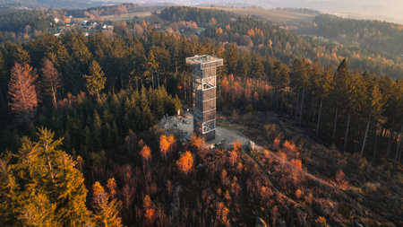 The wooden lookout tower at Cisarsky Kamen near Liberec offers stunning views during an autumn sunset, with colorful foliage and serene forest surroundings creating a peaceful atmosphere.の写真素材