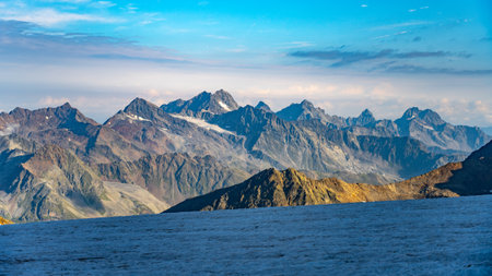 Snow-capped mountains rise majestically in the Austrian Alps, with clear blue skies creating a stunning backdrop. The rugged terrain showcases natures beauty and grandeur.の写真素材