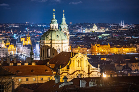 Church of St Nicholas stands majestically in Lesser Town, Prague, showcasing its Baroque architecture. The city skyline glows, highlighting its historical beauty at night.の写真素材