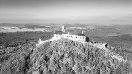 The aerial view captures a medieval castle surrounded by vibrant autumn foliage, showcasing its historical architecture against a backdrop of expansive landscapes.の写真素材