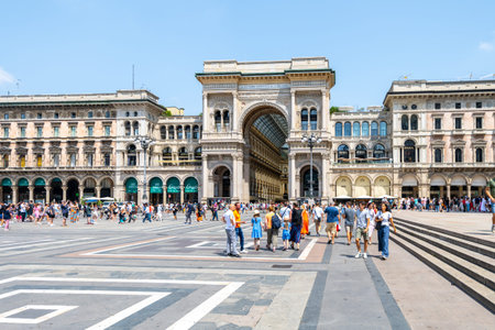 The entrance to Galleria Vittorio Emanuele II is bustling with visitors exploring the iconic architecture and shops on a sunny day in Milan, Italy, surrounded by vibrant crowds.の写真素材