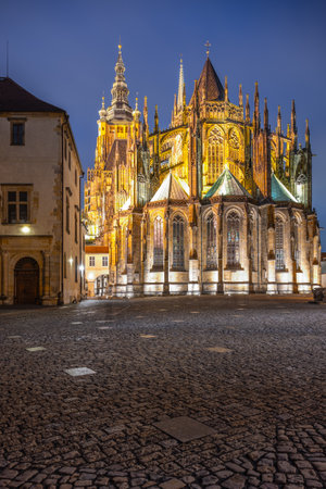 This view showcases the intricate ornamental details of the back side of St Vitus Cathedral, illuminated at dusk against the historic backdrop of Prague Castle.の写真素材