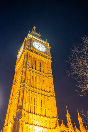 Big Ben stands tall and illuminated against the night sky in London, England. The historical clock tower showcases intricate architecture and glowing lights, creating a stunning night view.の写真素材