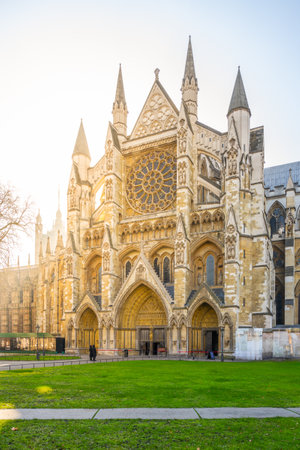 Visitors admire the intricate Gothic architecture of Westminster Abbey in London during a sunny day. The stunning rose window and detailed stonework create a magical atmosphere.の写真素材