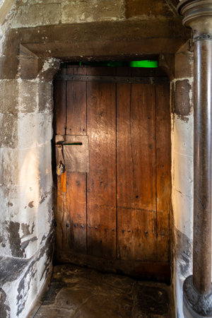 This historic wooden door is found in Westminster Abbey, London. It stands as a remarkable example of medieval craftsmanship, showcasing weathered wood and unique design elements.の写真素材