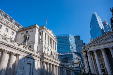 The historic Bank of England stands in London, showcasing its classic architecture against a backdrop of modern skyscrapers under a bright blue sky on a sunny day.の写真素材