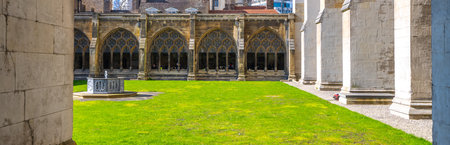 The lush, green lawn is framed by the historic cloisters of Westminster Abbey, showcasing Gothic architecture. Visitors enjoy the serene atmosphere amid the ancient stone walls and stained glass.の写真素材