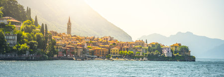 Menaggio sits gracefully along the shores of Lake Como, showcasing its charming architecture and stunning natural surroundings illuminated by warm sunlight, creating a picturesque experience.の写真素材