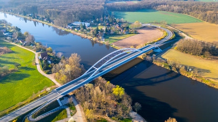 The modern Bohumil Hrabals Bridge connects two scenic banks over the Labe River in Litol, Lysa nad Labem. Lush green landscapes surround the bridge, showcasing natures beauty.の写真素材