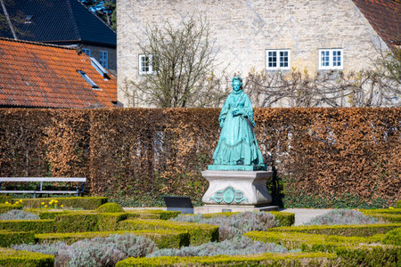 Queen Caroline Amalies statue stands gracefully in Rosenborg Castle Garden, surrounded by lush greenery and meticulously arranged hedges, inviting visitors to admire its beauty.の写真素材