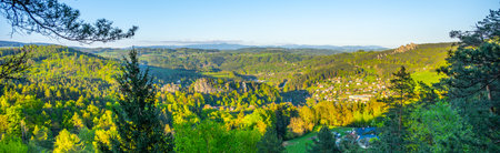 Visitors at Pantheon Lookout enjoy breathtaking views of Bohemian Paradise, featuring lush greenery and the impressive Krkonose Mountains in the background during a clear day.の写真素材