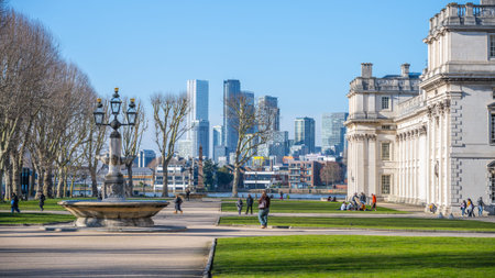 Visitors stroll through the grounds of the Old Royal Naval College in Greenwich, enjoying the views of the historic architecture and the modern London skyline in the distance.の写真素材