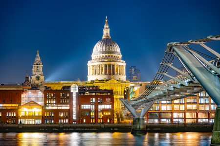 The tranquil evening at the River Thames showcases the stunning Millennium Bridge leading to the illuminated St. Paul's Cathedral, creating a picturesque London skyline.の写真素材