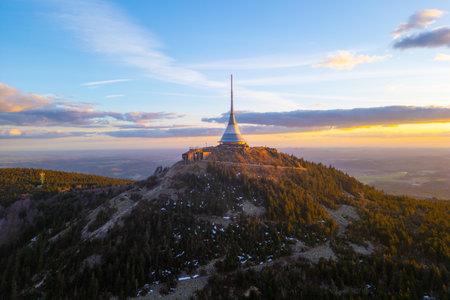 Spring colors illuminate Jested Mountain as the sun sets over Liberec. The iconic tower stands tall, surrounded by natures beauty and a serene atmosphere at dusk.の写真素材