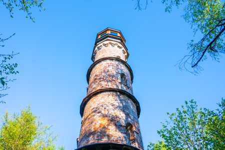 The Kopanina Lookout Tower rises majestically amidst lush greenery in Bohemian Paradise, Czechia. Visitors admire the scenic views from this historic structure under a clear blue sky.の写真素材