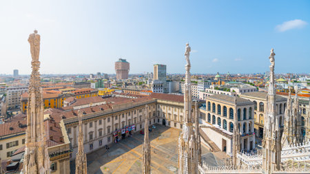 The breathtaking view from the rooftop of the Duomo reveals Milans vibrant skyline, featuring historic buildings, rooftops, and modern architecture under a clear blue sky.の写真素材