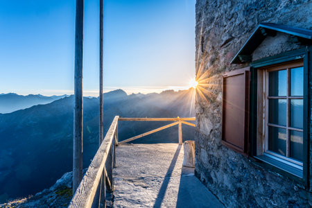 Morning light casts a warm glow on the Julius Payer House, set in the Ortler Alps. The stunning mountain backdrop enhances the serene atmosphere of this remote lodge.の写真素材