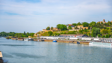 The Sava River flows peacefully through Belgrade, offering scenic views of green hills and historic architecture. Boats navigate the water while people enjoy the tranquil atmosphere.の写真素材