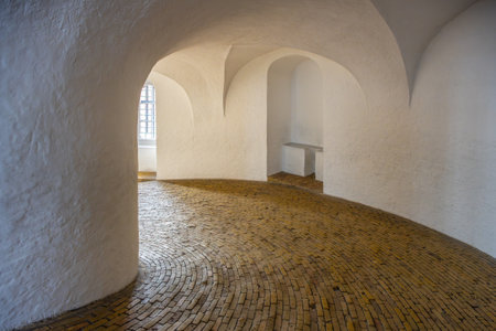 Visitors explore the winding, wooden-floored spiral ramp of Round Tower in Copenhagen. This historic structure offers unique architectural elements and stunning views from the top.の写真素材