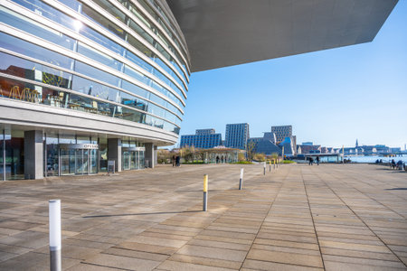 Visitors take advantage of a sunny day at Copenhagen Opera House, strolling along the buildings...