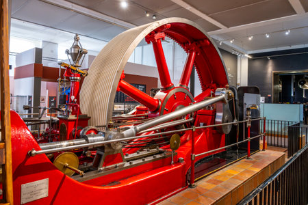 A large red mill engine is showcased at London's Science Museum. Visitors can observe this impressive piece of engineering from various angles.の写真素材
