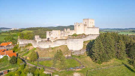 Rabi Castle ruins stand majestically against the backdrop of Czech countryside. This drone view showcases the historical structure surrounded by lush greenery and distant hills on a clear day.の写真素材