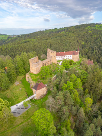 Aerial view captures the majestic ruins of Velhartice Castle surrounded by lush greenery and forest during spring. The tranquil setting highlights the historical significance and natural beauty.の写真素材