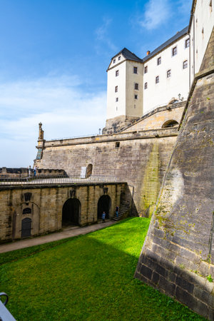 A bright day at Konigstein Fortress reveals its impressive architecture and scenic grounds. Visitors wander through the historical site while enjoying the beautiful surroundings.の写真素材