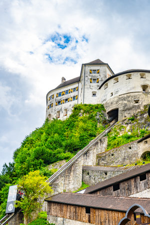Kufstein Fortress stands majestically atop a hill in Tyrol, Austria, showcasing its historical architecture. Lush greenery surrounds the fortress, contrasting with the cloudy sky.の写真素材