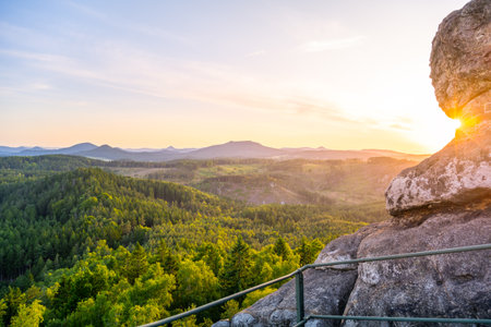The Lusatian Mountains offer a breathtaking view from Popov Cliffs during the evening. The sandstone formations shine under the soft glow of the sunset, creating a peaceful atmosphere.の写真素材
