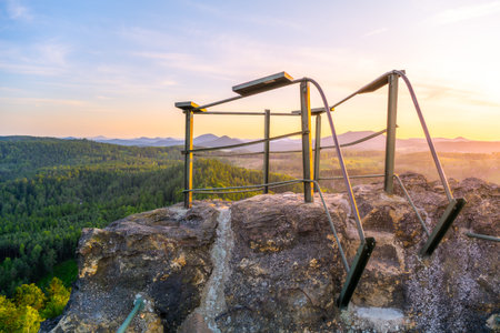 Enjoy a breathtaking sunset over the Lusatian Mountains from the rocky vantage point of Popov Cliffs. The warm evening light casts a golden hue across the sandstone formations and lush forests.の写真素材