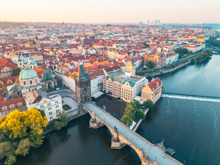 The stunning Charles Bridge stretches across the Vltava River, connecting historic sites in Prague. Old Town Bridge Tower rises majestically, complementing the scenic urban landscape at sunset.の写真素材