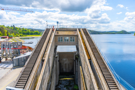 View of the impressive boat lift at Orlik Dam, which efficiently elevates vessels between different water levels. The location features serene water and lush greenery under a partly cloudy sky.の写真素材
