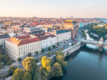 Smetanas Embankment along the Vltava River showcases stunning architecture and vibrant city life in Prague during a beautiful sunset. The scenic river reflects the surrounding historic buildings.の写真素材