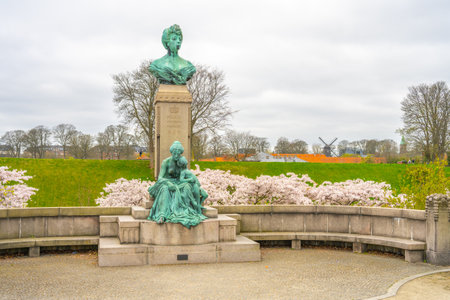 The statue of Princess Marie stands gracefully at Kastellet, surrounded by lush greenery and blooming cherry blossoms. The tranquil setting enhances the statues beauty on a cloudy day.の写真素材