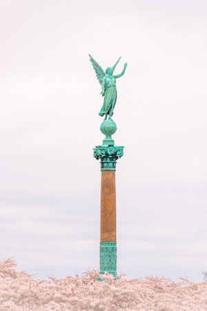 Ivar Huitfeldt Column towers at Langelinie in Copenhagen, showcasing its green statue of an angel against a serene sky, surrounded by blooming flowers creating a peaceful atmosphere.の写真素材