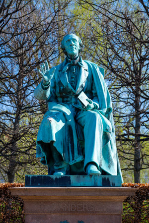 A statue of Hans Christian Andersen sits gracefully in Rosenborg Castle Gardens, surrounded by lush trees and vibrant greenery, capturing the essence of storytelling in Copenhagen.の写真素材