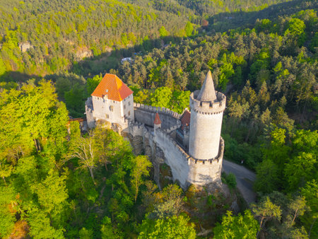 Kokorin Castle is bathed in warm evening sunlight, surrounded by lush greenery. The aerial view showcases the castles impressive structure and natural beauty of the Czech landscape.の写真素材