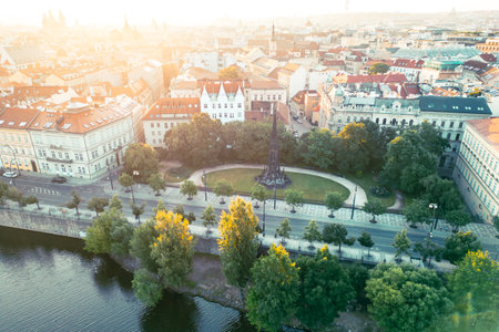 Visitors admire Kranners Fountain surrounded by lush greenery in the Park of the National Awakening, overlooking the Vltava River and historic buildings of Prague during sunset.の写真素材