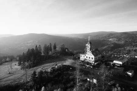 The Tanvaldsky Spicak Lookout Tower stands proudly in the Jizera Mountains, surrounded by vibrant autumn foliage as the sun sets, casting a warm glow over the landscape.の写真素材