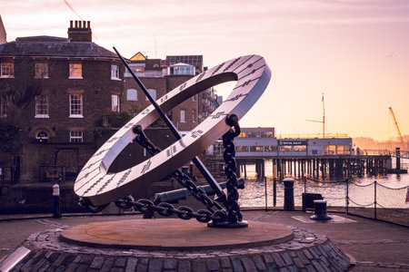 The Timepiece Sundial stands prominently along the Thames River in London, offering a unique way to tell time. Surrounded by historic buildings, it captures the essence of the citys charm at sunset.の写真素材