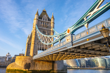 Early morning sunlight illuminates Tower Bridge, creating a stunning view over the Thames River. The iconic structure blends history with the vibrant atmosphere of London.の写真素材