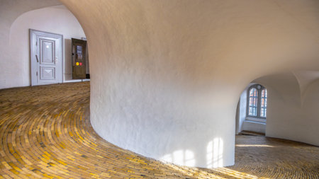 Visitors ascend the spiral ramp of the Round Tower in Copenhagen, Denmark, experiencing its smooth winding pathway and light-filled interior. This architectural marvel offers stunning views.の写真素材